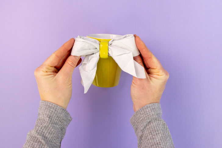 Serviette an Henkel einer Tasse binden