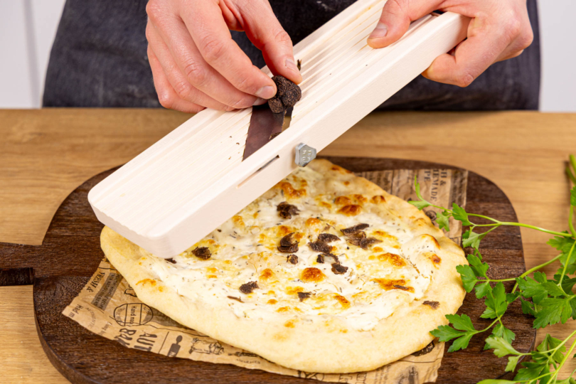 Trüffelpizza mit frischen Trüffel und Petersilie garnieren