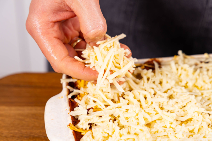 veganen Streukäse mit Öl mischen und über die Lasagne streuen
