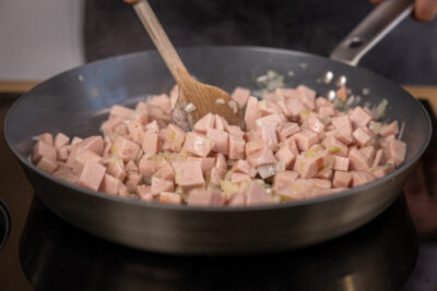Zwiebeln und Fleischwurst in der Pfanne anschwitzen