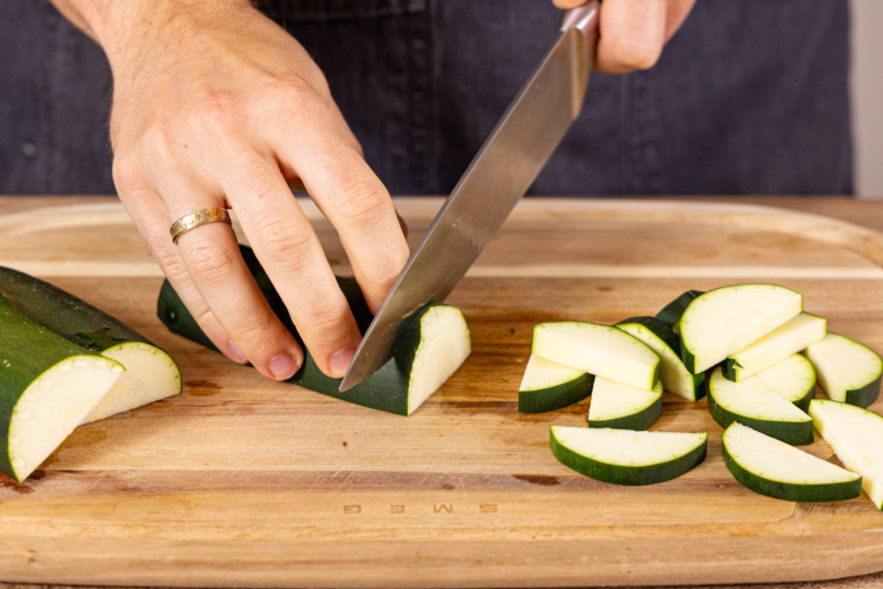 Zucchini halbieren und in Scheiben schneiden