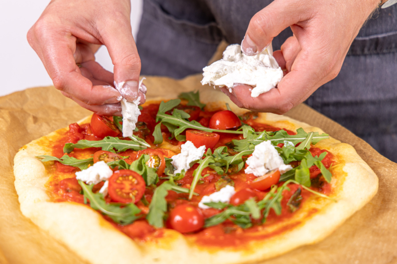Pizza mit Burrata und Rucola belegen