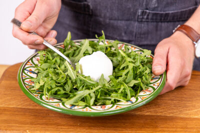Burrata auf dem rucola platzieren