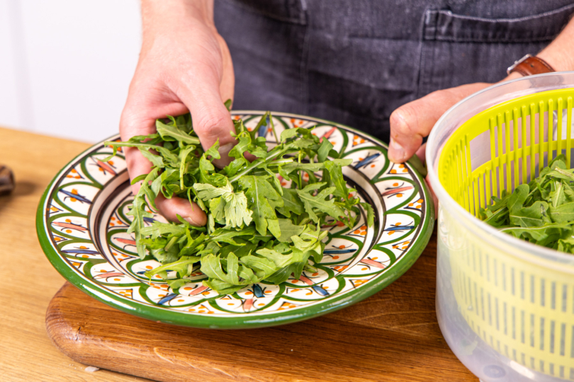 gewaschenen Rucola auf einem Teller anrichten