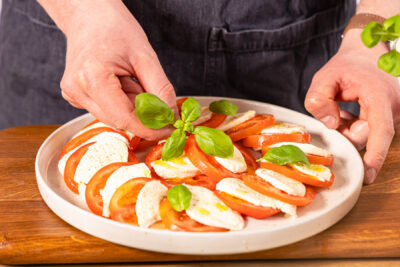 Caprese-Salat mit Basilikum toppen