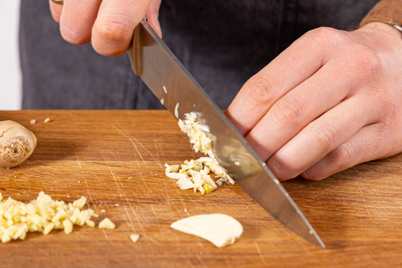 Knoblauch und Ingwer schälen und in feine Würfel hacken