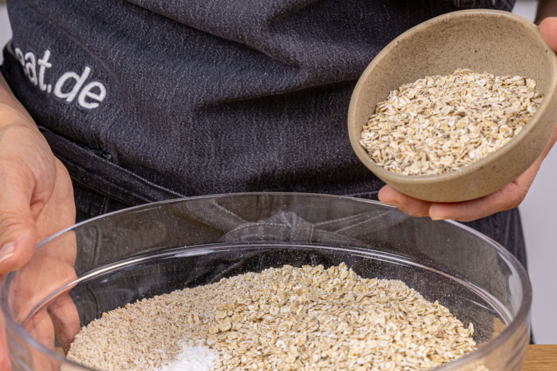 Haferflocken in Schüssel geben