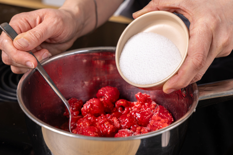 Zucker zu den Himbeeren geben