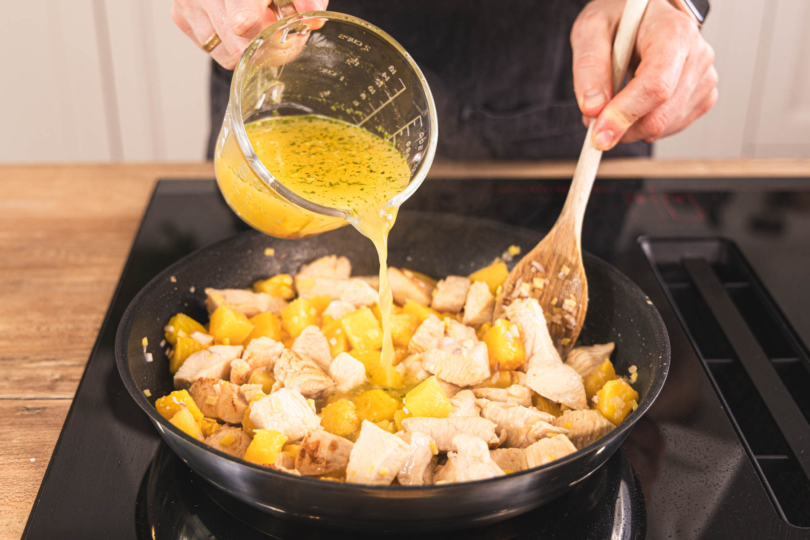 Fond zum Madras Chicken Curry gießen