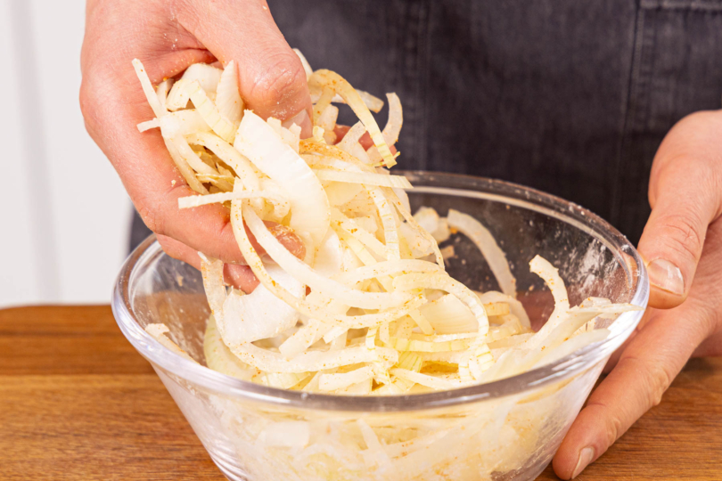 Zwiebelringe gleichmäßig mit Mehl und Öl vermengen