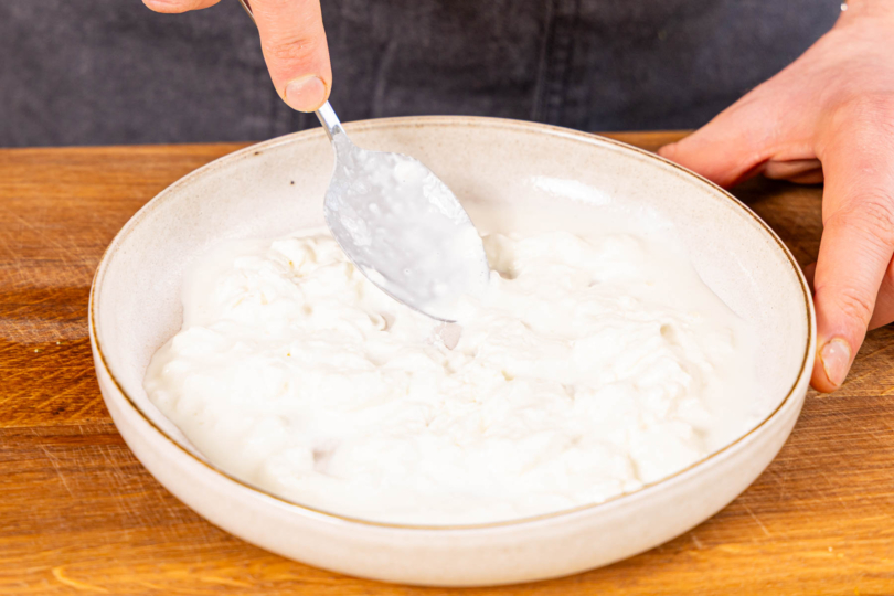 Stracciatella di Burrata auf einem Teller verstreichen