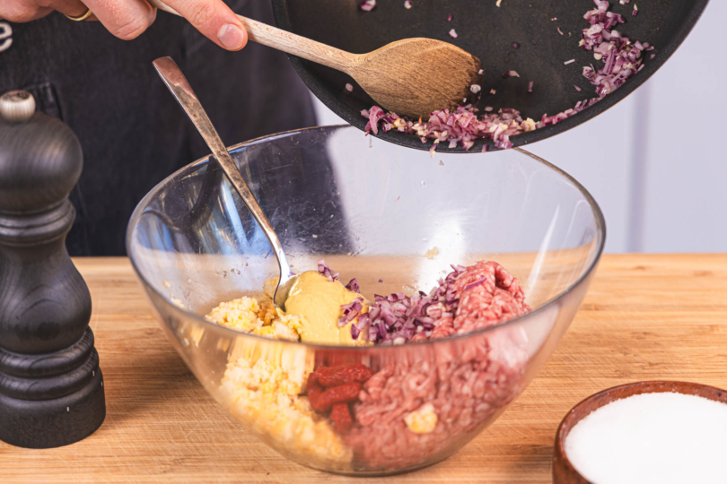 Zwiebel und Knoclauch zum Hackfleisch geben