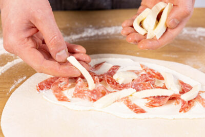 Calzone mit Salami und Mozzarella belegen