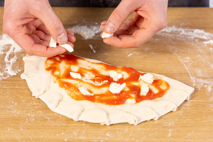 geschlossene Calzone mit Soße und Mozzarella belegen