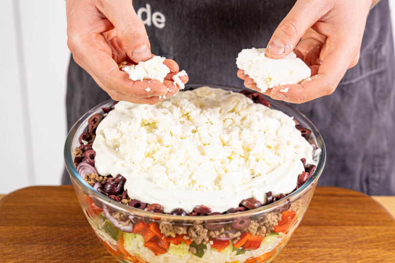 Tzatziki und Feta auf dem Salat verteilen