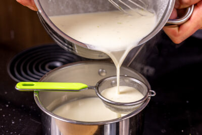 Panna-Cotta-Masse durchs Sieb gießen, um Limettenschale zu entfernen