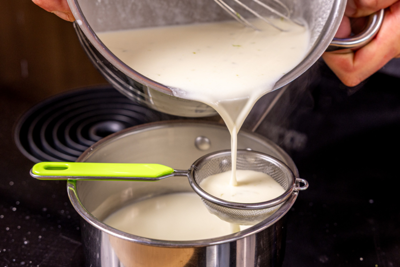 Panna-Cotta-Masse durchs Sieb gießen, um Limettenschale zu entfernen
