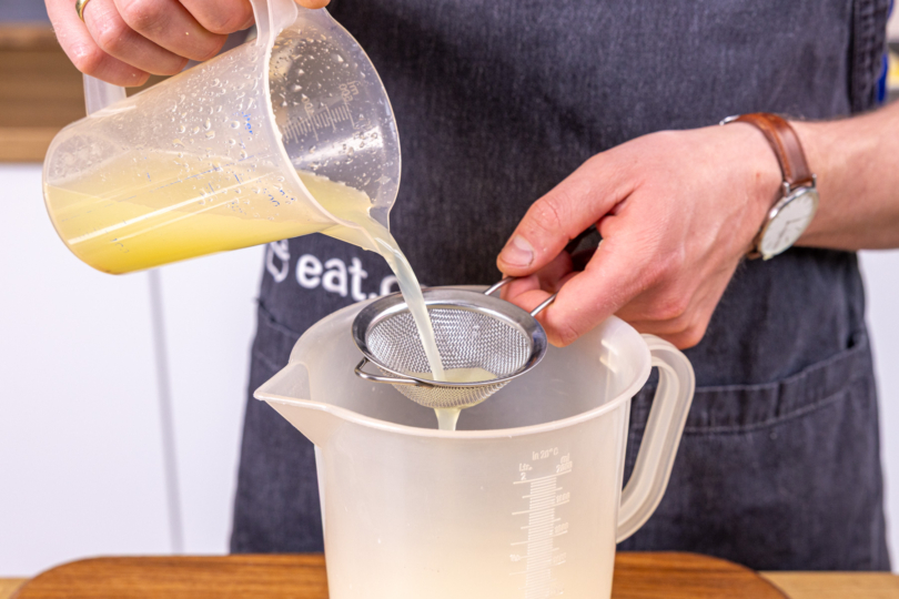Zitronensaft durchs Sieb zur Milchmasse geben