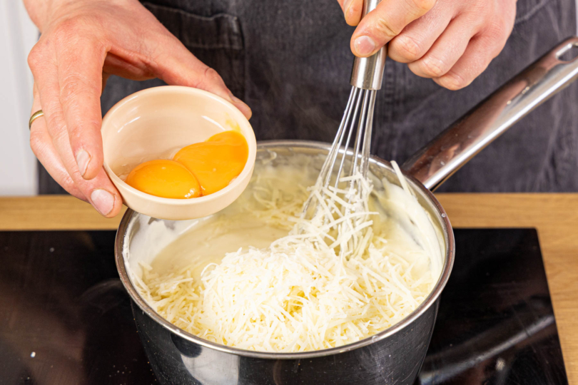 Käse und Eigelbe zur Béchamel geben
