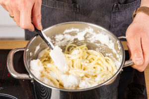 Nudeln mit Einschnee und Käse vermengen