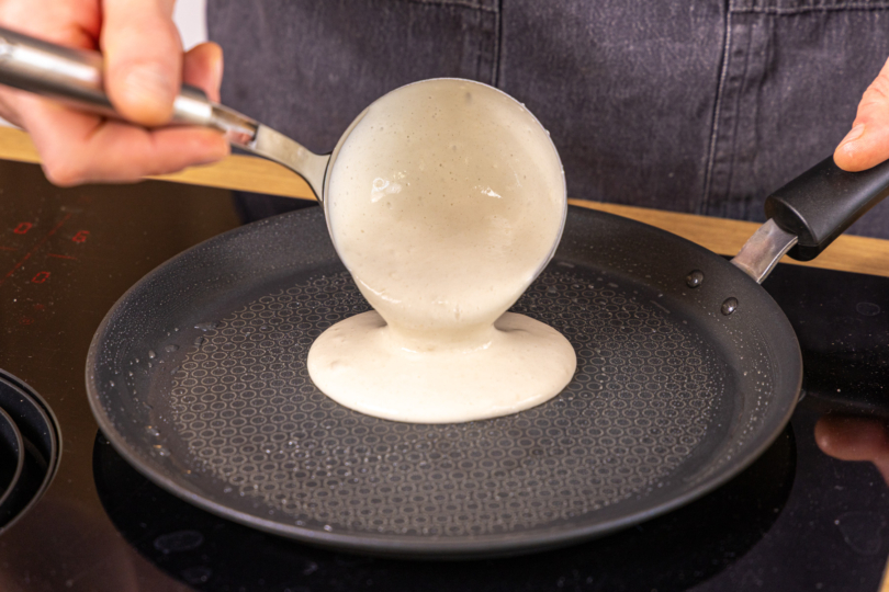 Teig mit einer Kelle in die heiße Pfanne geben