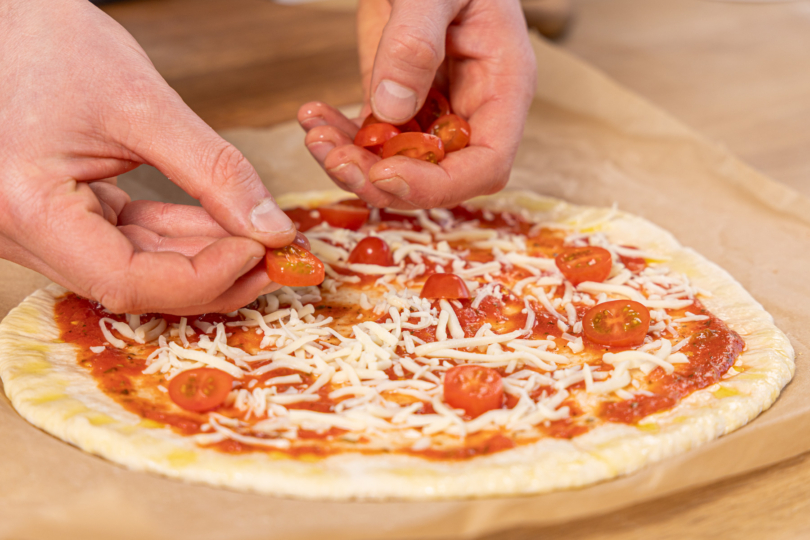 Tomatenscheiben auf der Pizza verteilen