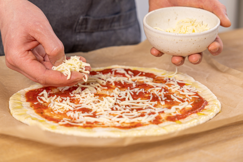 Mozzarella auf der Pizza verteilen