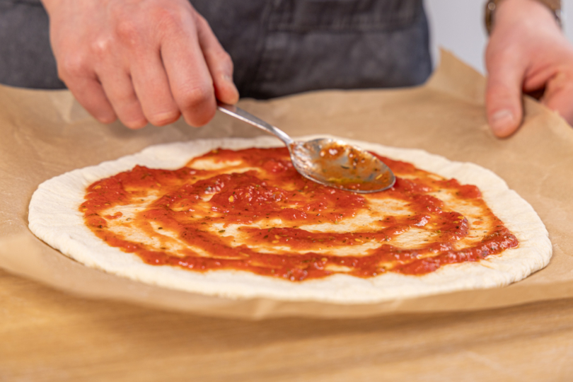 Pizza mit Tomatensauce bestreichen