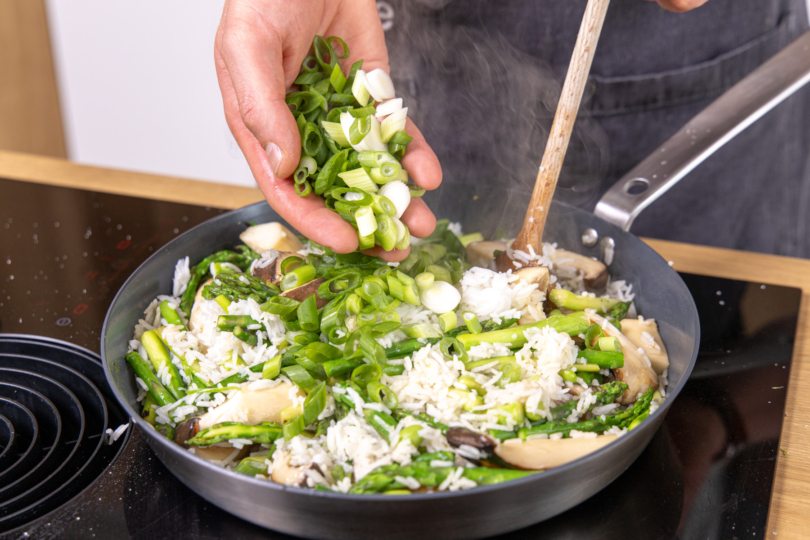 Reispfanne mit grünem Spargel mit Frühlingszwiebel servieren