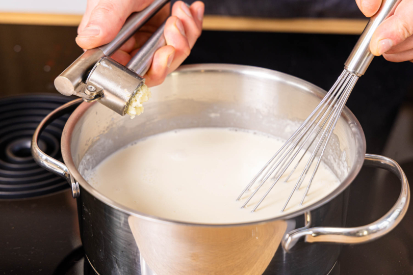 Knoblauch zur Bechamelsauce pressen