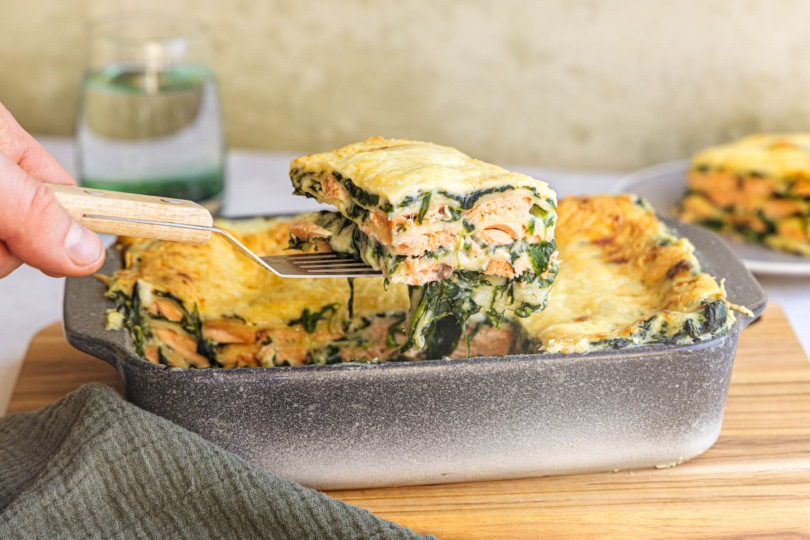 Stück Spinatlasagne mit Lachs aus der Form heben