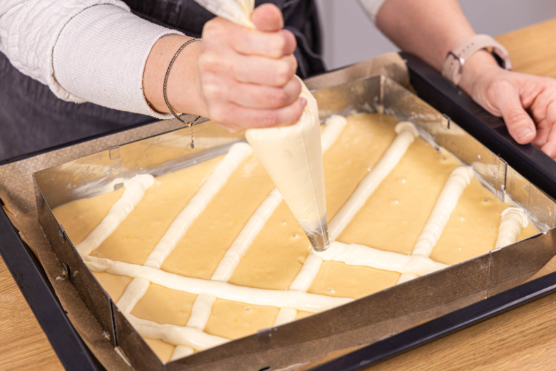 Quarkmasse als Gitter auf den Steppdeckenkuchen spritzen
