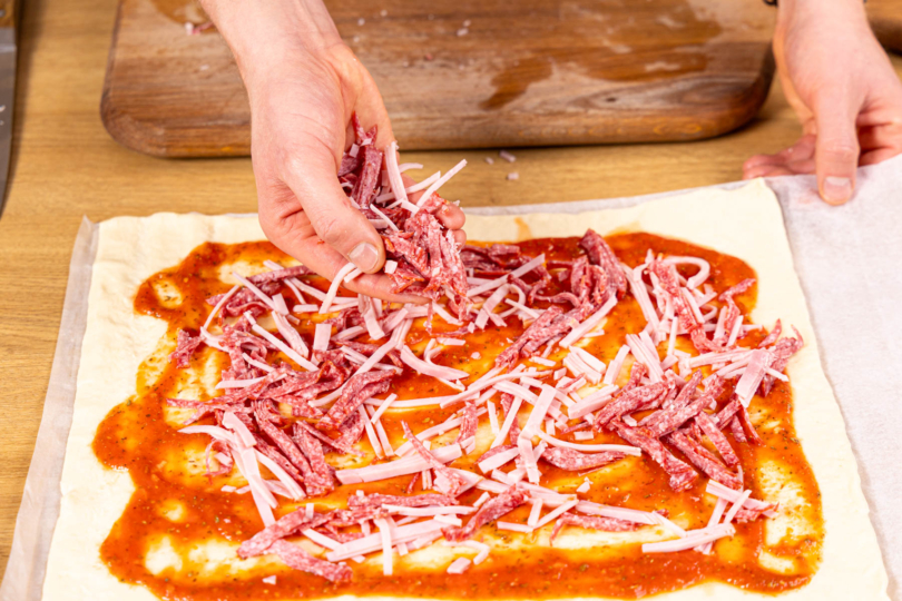 geschnittene Wurst auf der Pizza verteilen