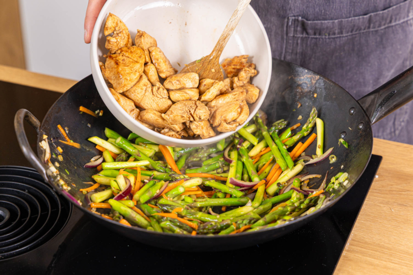 gebratenes Hähnchen zum Gemüse in den Wok geben