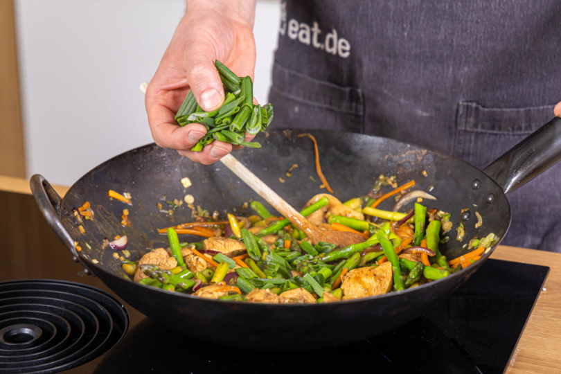 dunkelgrünen Teil der Frühlingszwiebel zur Wok-Pfanne geben