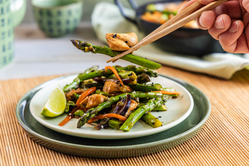 grünen Spargel und Hähnchen mit Stäbchen von der asiatischen Wok-Pfanne holen