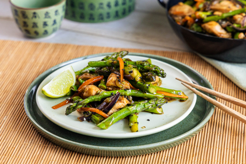 Asiatische Wok-Pfanne mit grünem Spargel und Hähnchen auf einem Teller