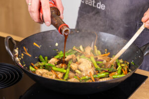 Teriyaki-Sauce zur asiatischen Wok-Pfanne geben