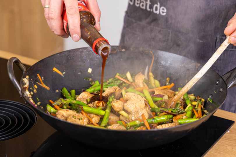 Teriyaki-Sauce zur asiatischen Wok-Pfanne geben