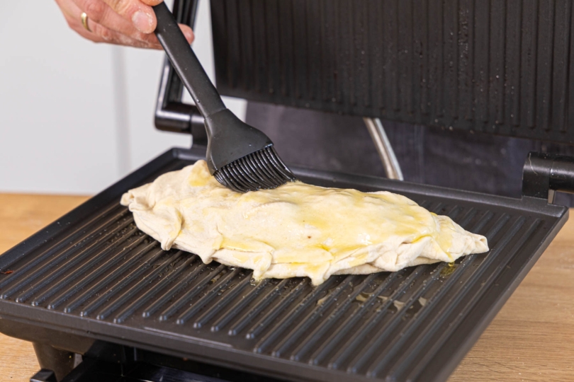 Calzone im Kontaktgrill mit Öl bestreichen