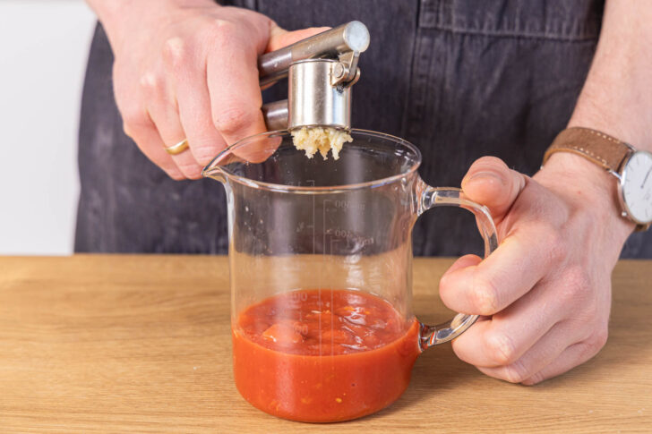 Knoblauch zu den gehackten Tomaten pressen