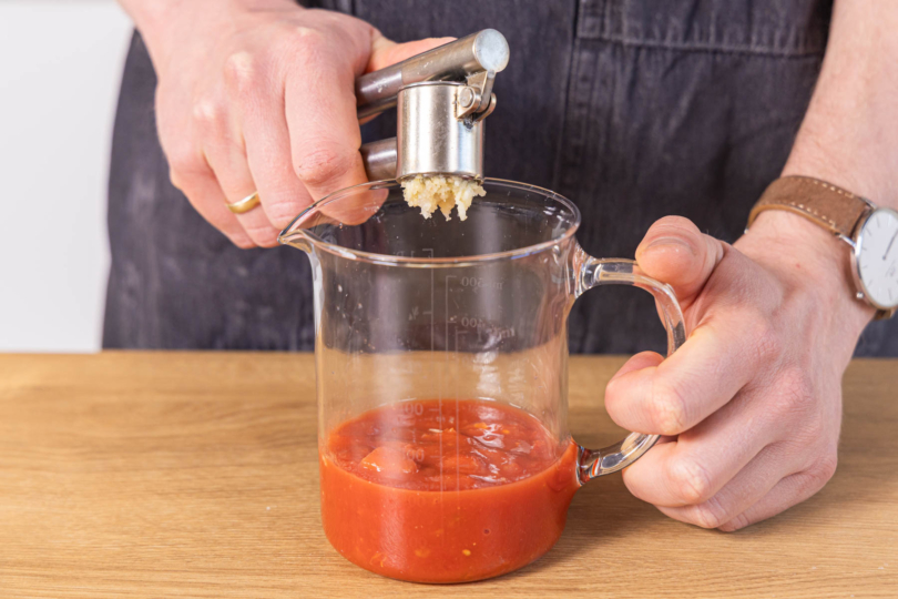 Knoblauch zu den gehackten Tomaten pressen