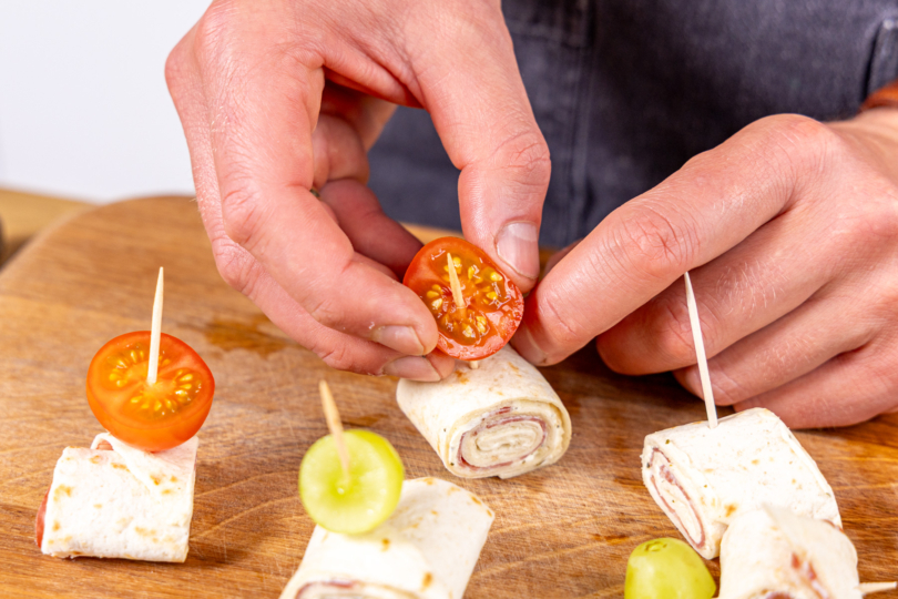 Tomate auf Wrap-Käse-Spieß spießen