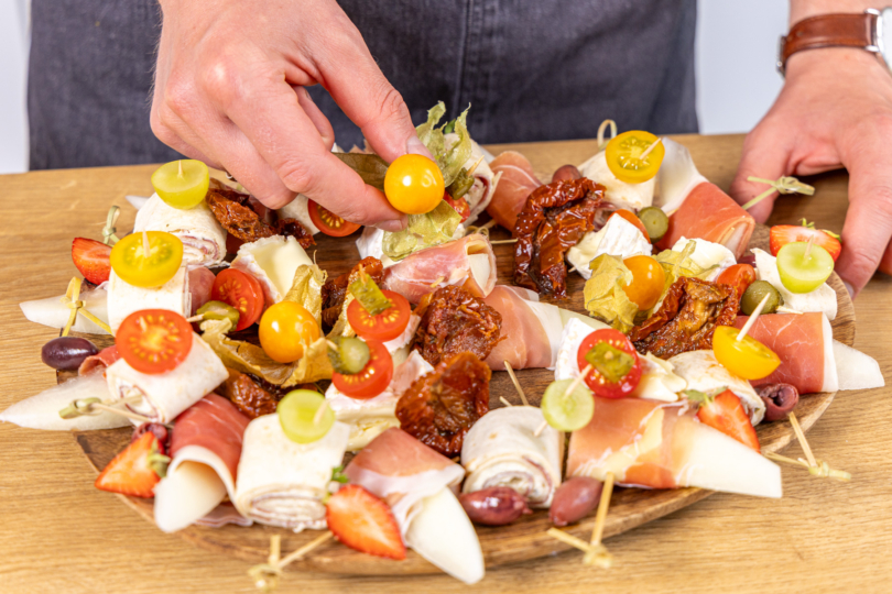 Käsespieße anrichten und mit Nüssen, Antipasti und Co. dekorieren