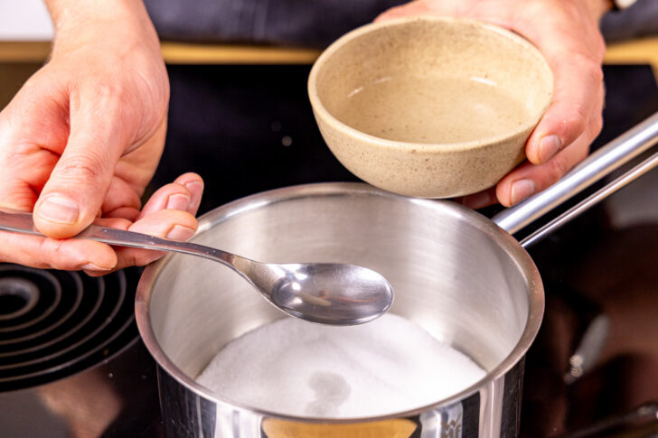 Wasser zum Zucker in den Topf geben