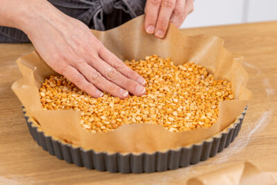 Hülsenfrüchte zum Blindbacken auf Backpapier auf der Tarte
