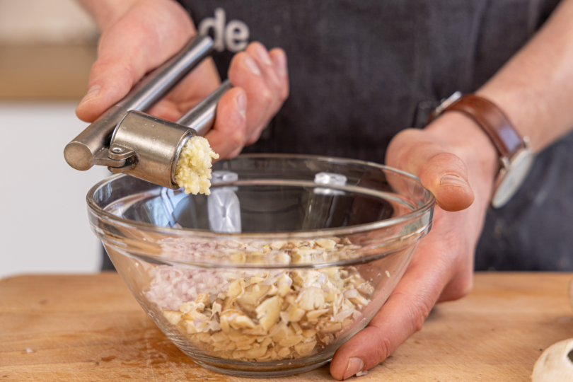 Knoblauch in die Schüssel pressen