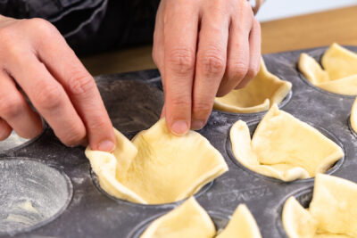 Pizzateig in die Formen geben