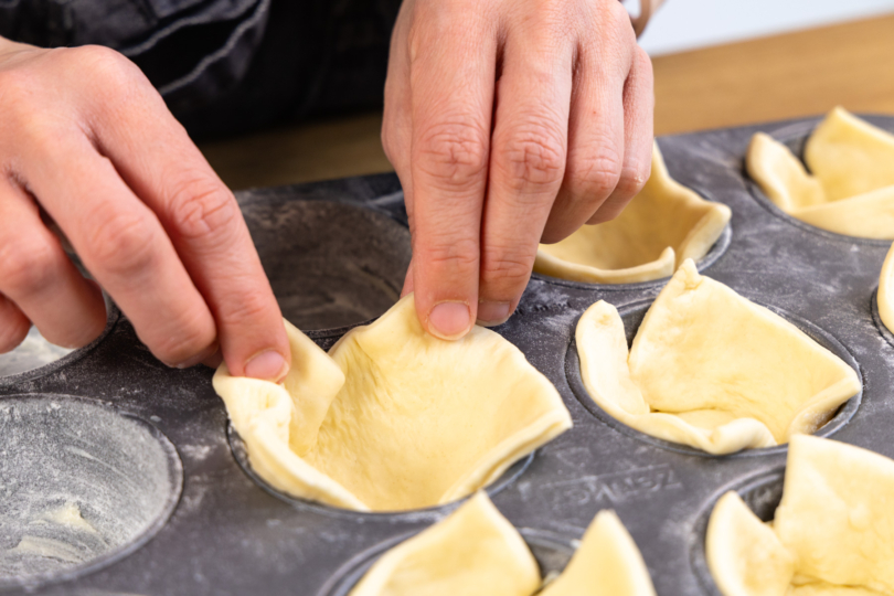 Pizzateig in die Formen geben