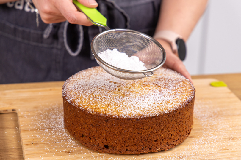 Orangenkuchen mit Puderzucker bestäuben